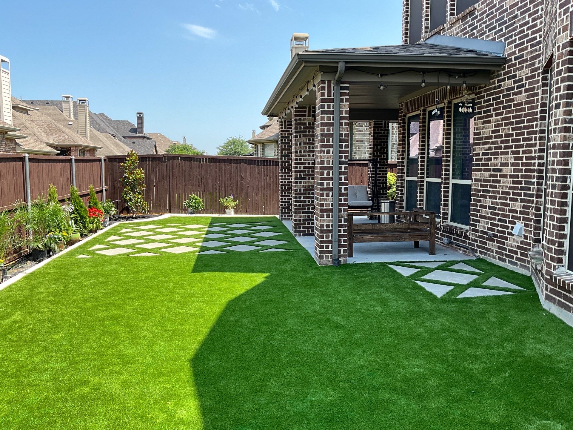 turf design ideas for a backyard with a real garden along the edges and pavers to the covered patio.