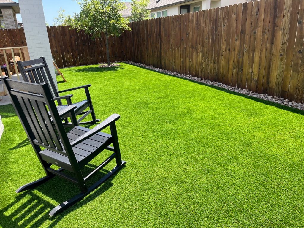 Low maintenance yard with artificial turf and dark brown rocking chairs