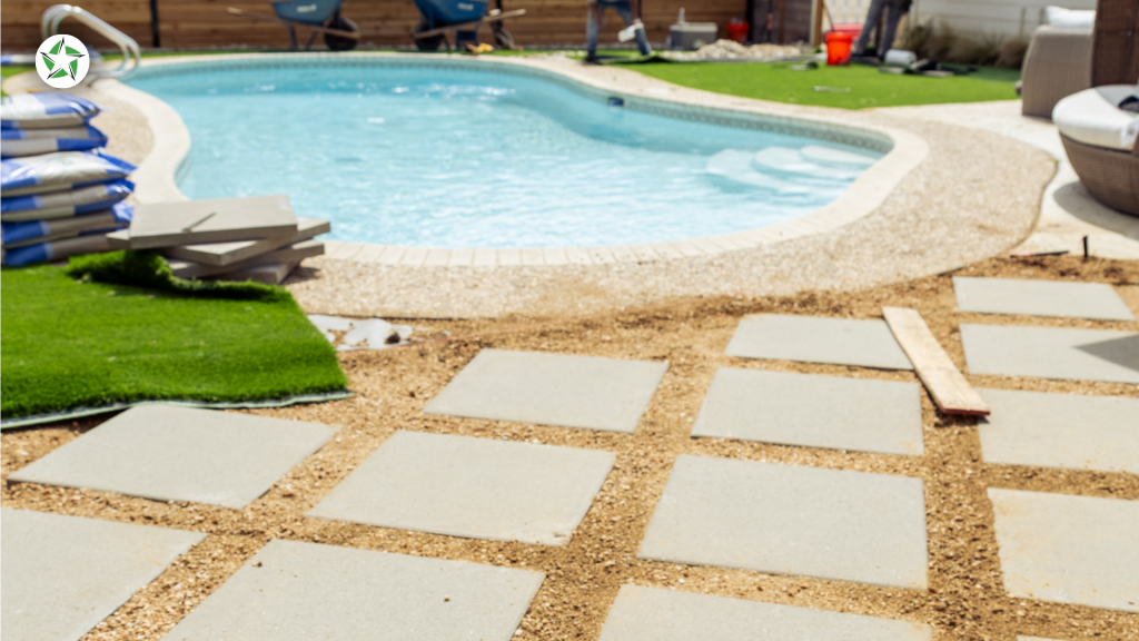 Paver installation in progress beside a pool with turf staged nearby, Lone Star Turf Texas, from Turf Around the Pool: Pavers vs. Concrete vs. Turf.