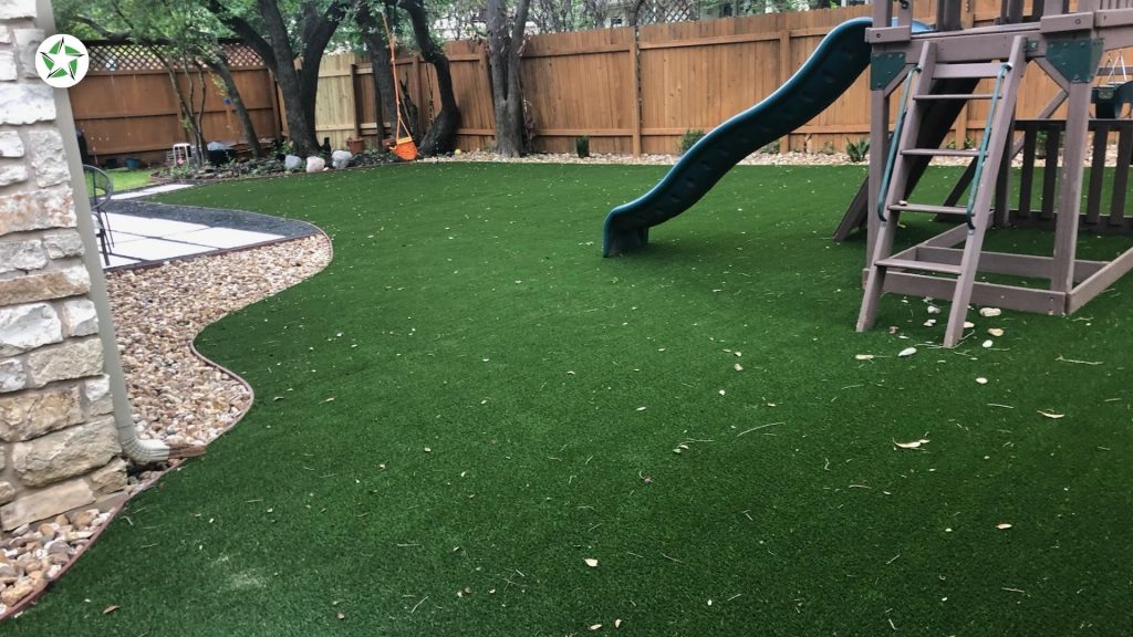 Fallen leaves and twigs scattered across a shaded turf lawn beside a playset in the fall of year one with artificial turf, Year One With Artificial Turf: What to Expect, Lone Star Turf Texas