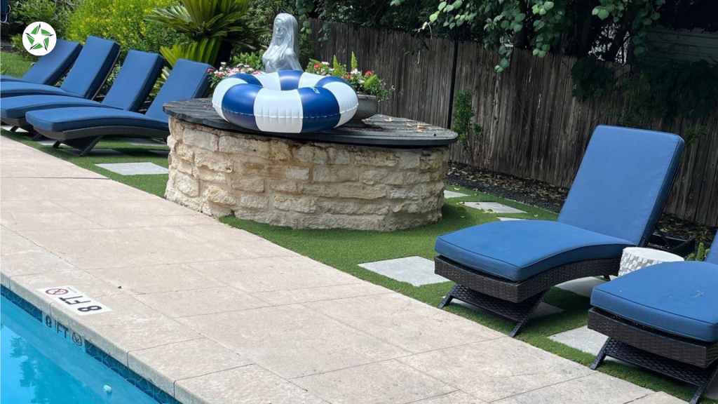 Lounge chairs on pavers beside turf around the pool and a stone fire pit, Lone Star Turf Texas, from Turf Around the Pool: Pavers vs. Concrete vs. Turf.