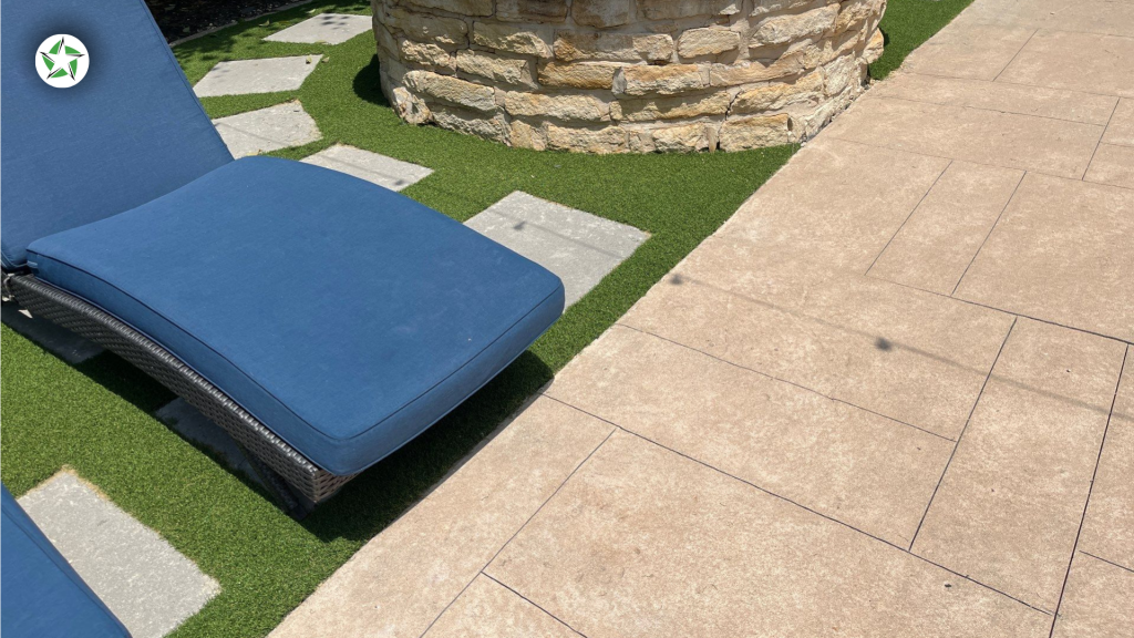 Close-up of pavers and turf around the pool next to a stone fire pit base, Lone Star Turf Texas, Turf Around the Pool: Pavers vs. Concrete vs. Turf.