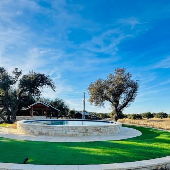 Artificial turf installed in a circle around a stone reflecting pool.