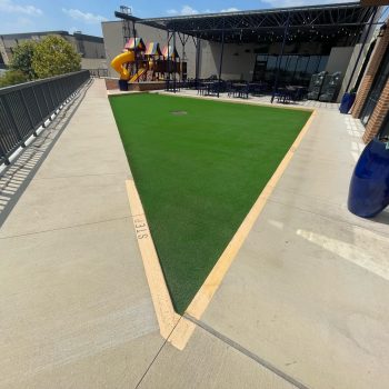 Triangular patch of artificial grass installed next to a restaurant outdoor seating area