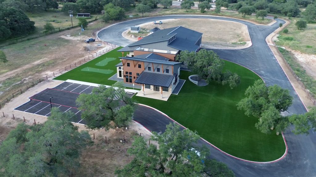 Aerial view from a drone of the Nickel Rock HQ, showcasing the large area of artificial turf out front for aesthetics and the two putting greens in the back.