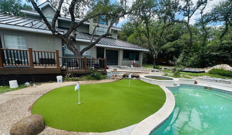 Low maintenance landscaping using artificial turf for a backyard putting green next to a pool.