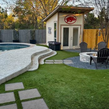 Low maintenance yard with artificial turf around a pool, fire pit, and shed.