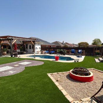 Backyard with artificial turf with zones for a pool, a pergola, a fire pit, and play.