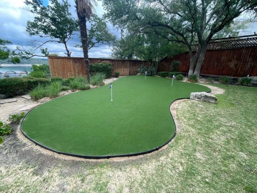 Backyard putting green with 3 holes, in roughly the shape of a kidney bean.