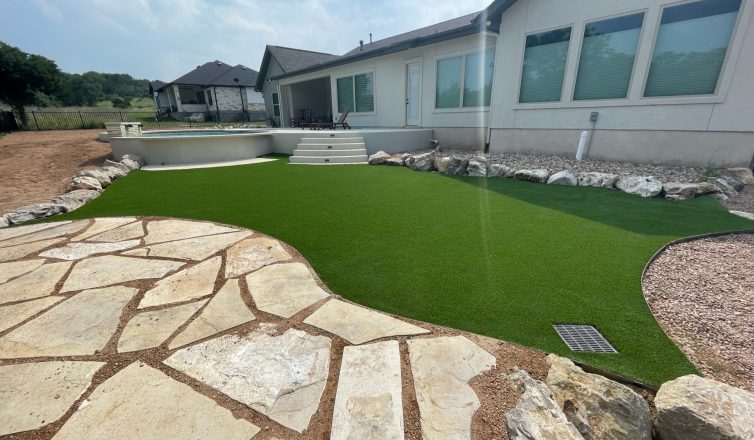 Artificial turf installation in backyard with stone feature and above ground pool.