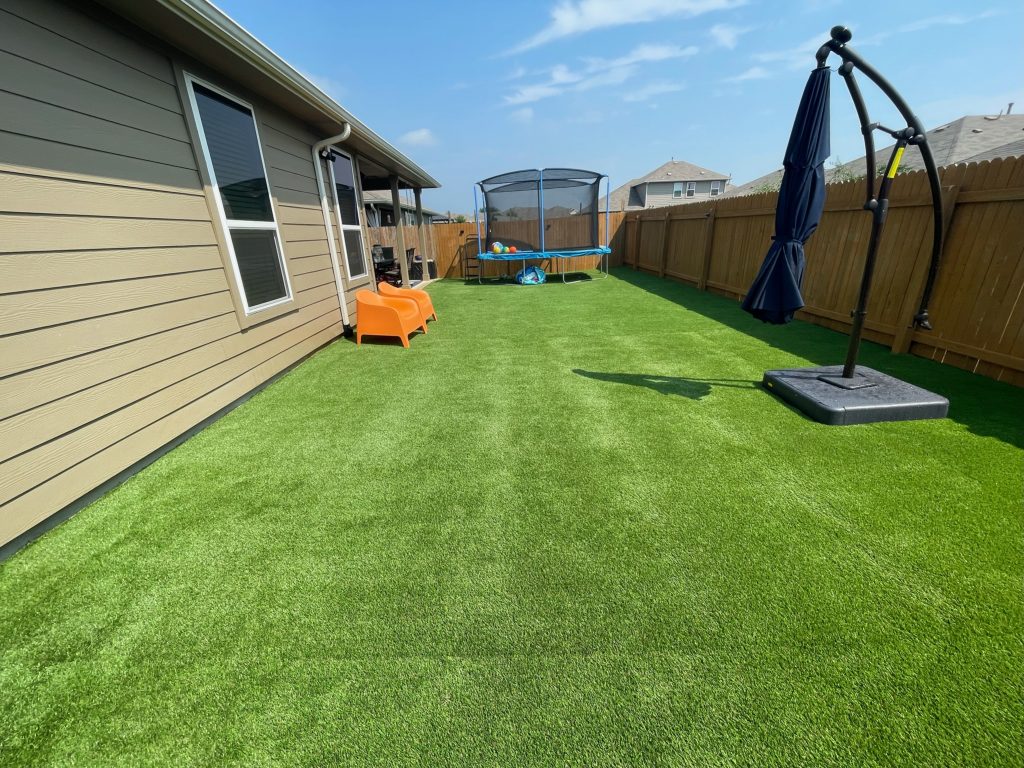 artificial turf in a backyard with a closed umbrella and play equipment