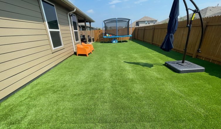 artificial turf in a backyard with a closed umbrella and play equipment