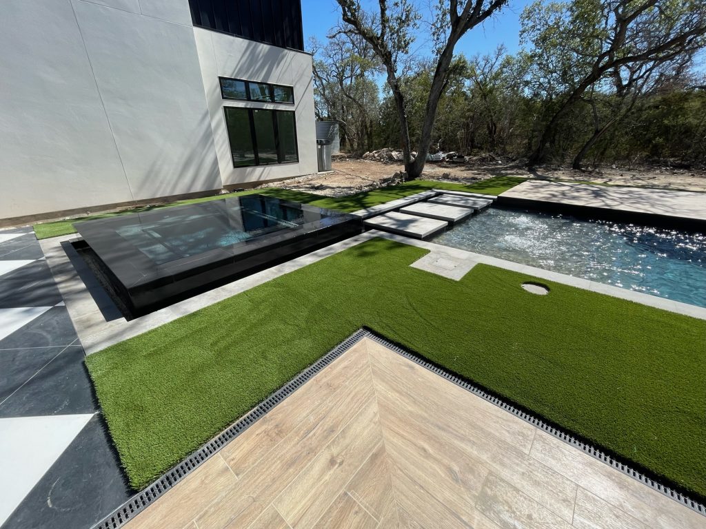 Turf installed around a pool and other stone tile and water features.