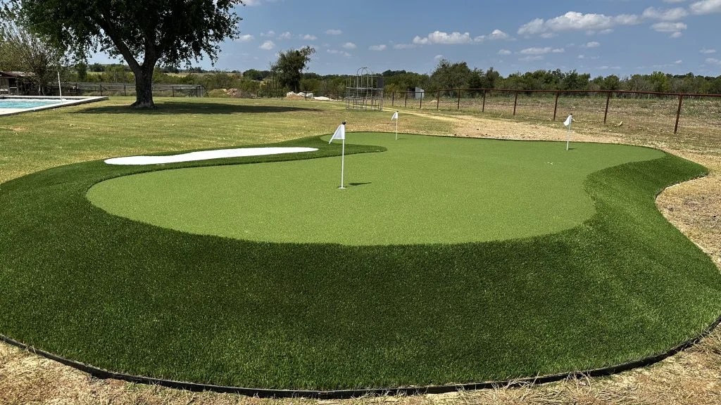 Large artificial turf putting green with three holes and a sand trap, one of the top Christmas gifts for golfers.
