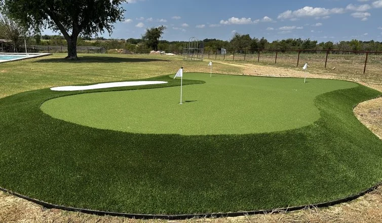 Large artificial turf putting green with three holes and a sand trap, one of the top Christmas gifts for golfers.