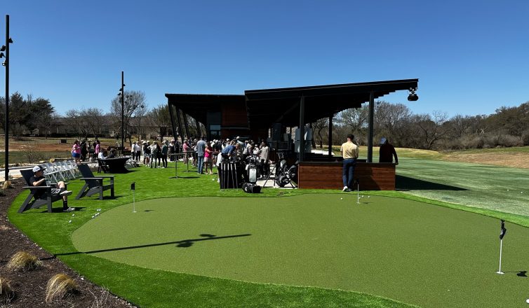 crowds gathered at a putting green and golf range with artificial turf installed