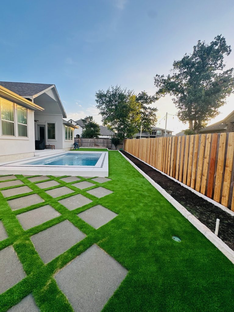 Backyard artificial turf design ideas with pavers by a pool.