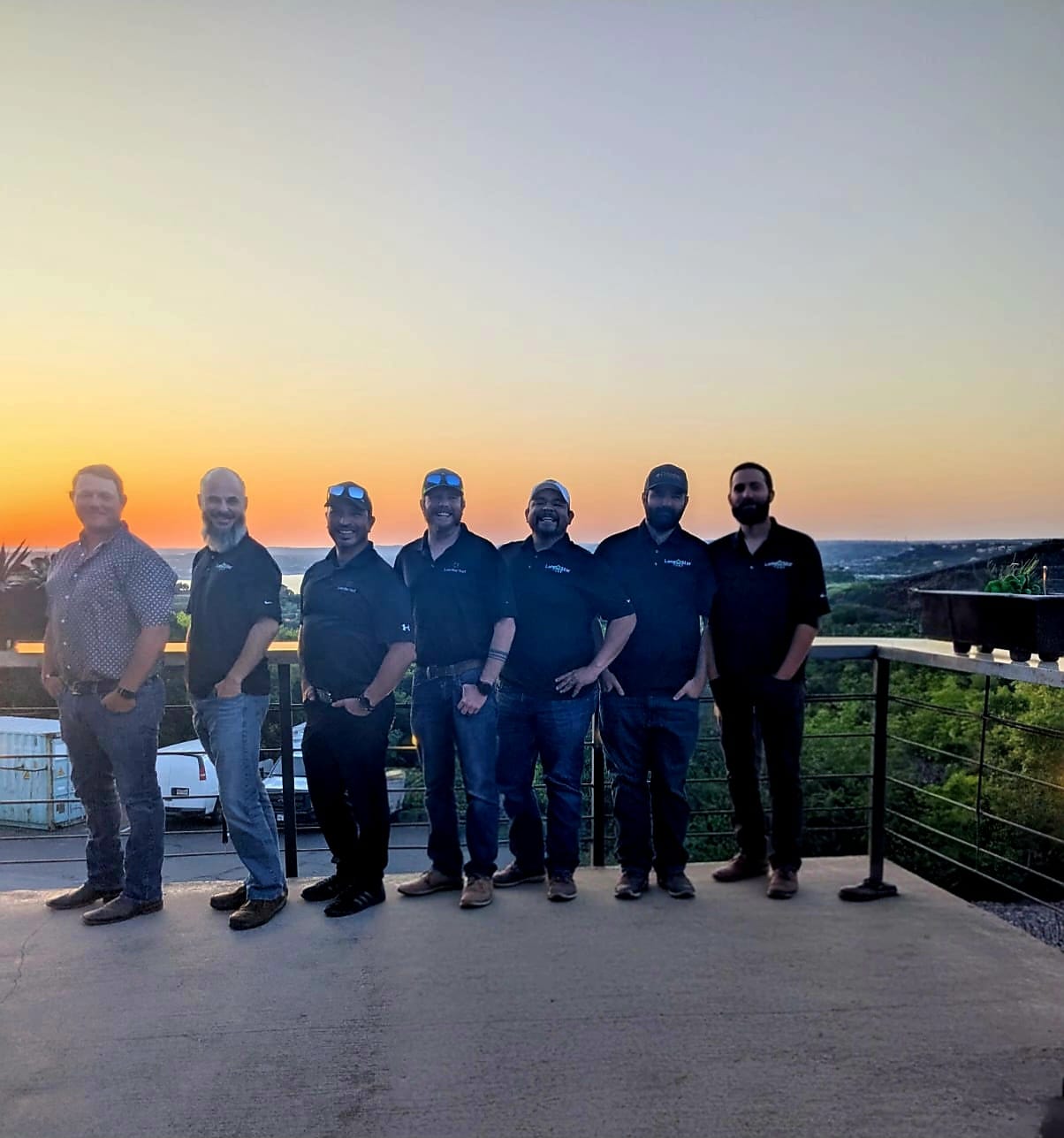 Lone Star Turf Team Group Photo A group of 7 men on the Lone Star Turf team, posing in a line for the photo in front of a sunset.