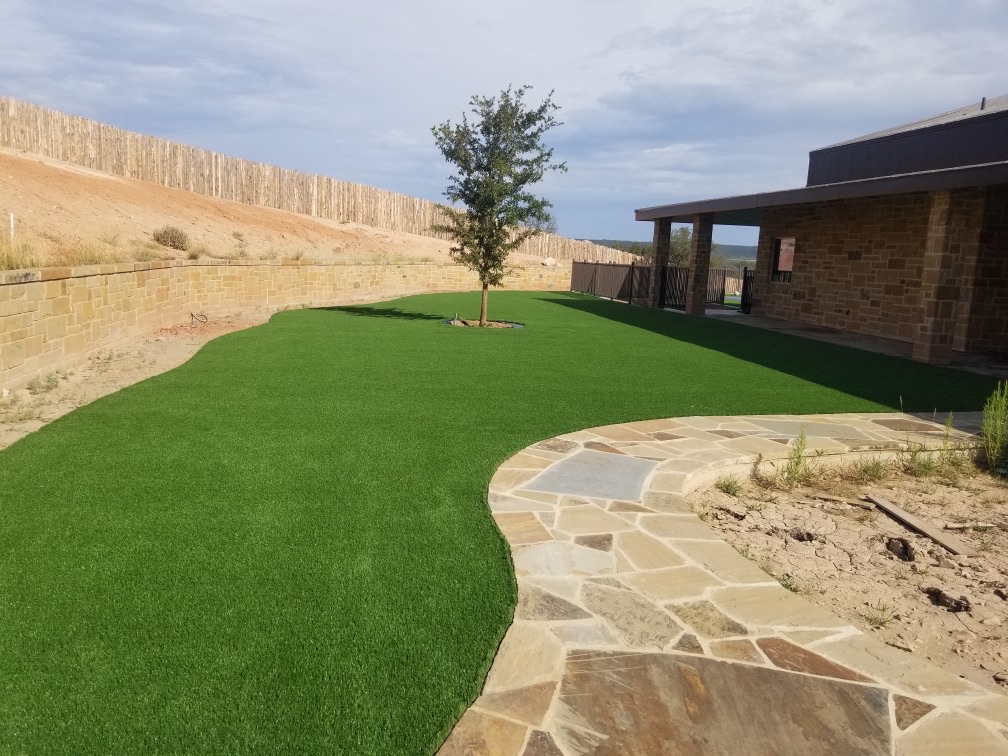Artificial turf installation with flagstone patio and retaining wall in a dry Texas landscape — How Much Does Artificial Turf Cost in Lakeway 2026 Guide by Lone Star Turf